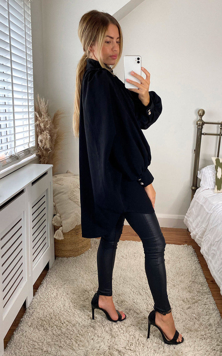 Woman in black oversized high-neck shirt taking a mirror selfie, showcasing the shirt's relaxed fit and stylish design for versatile wear.