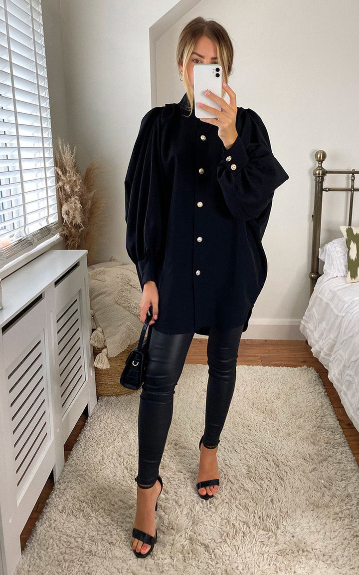 Woman wearing an oversized high-neck shirt, taking a selfie indoors. The shirt features a relaxed fit, perfect for casual or sophisticated styling.