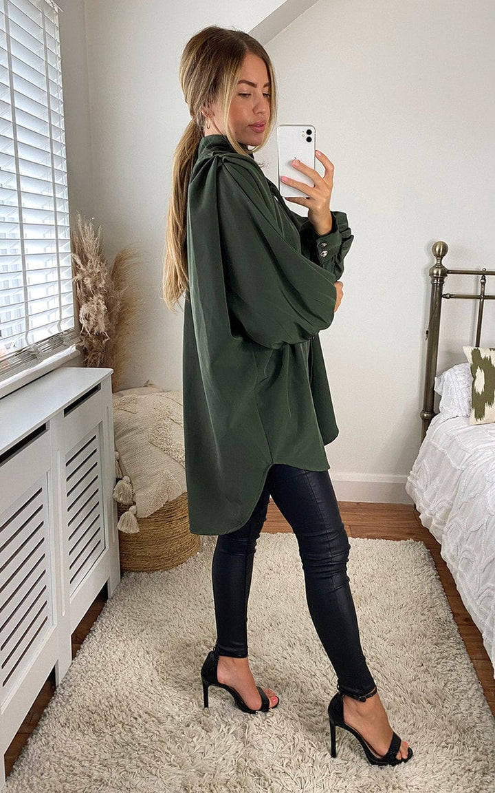 Woman wearing an oversized high neck shirt, taking a selfie indoors, showcasing the shirt's relaxed fit and stylish design.