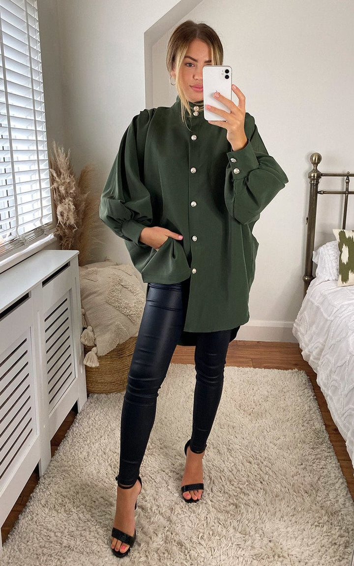 Woman wearing an oversized high neck shirt, capturing a selfie, showcasing the shirt's relaxed fit and elegant style.