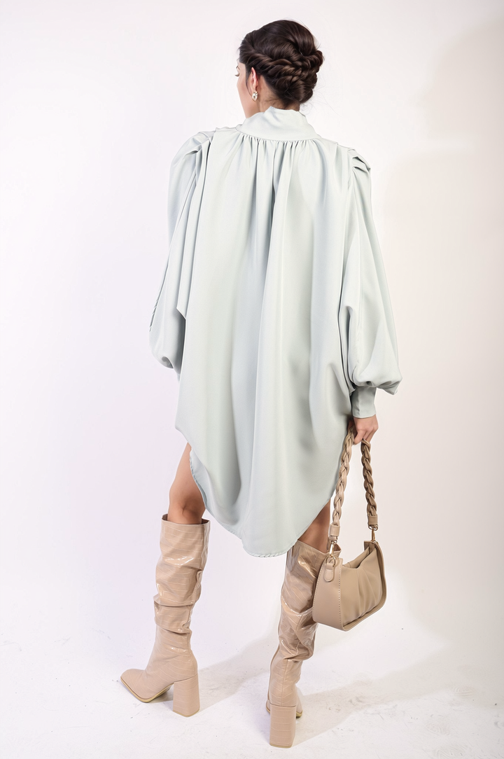 Woman wearing an Oversized High Neck Shirt with a relaxed fit, holding a purse, styled with boots. Perfect for casual or sophisticated looks.