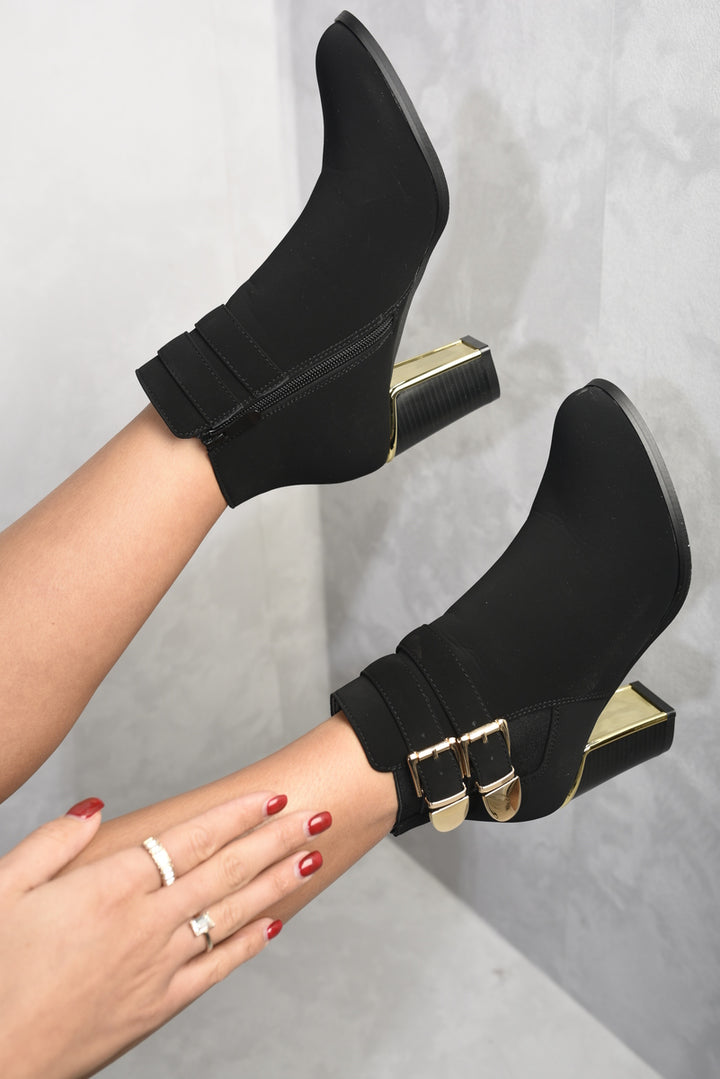 Black high-heeled ankle boots with buckle straps, featuring a block heel and side zip, designed for style and comfort.