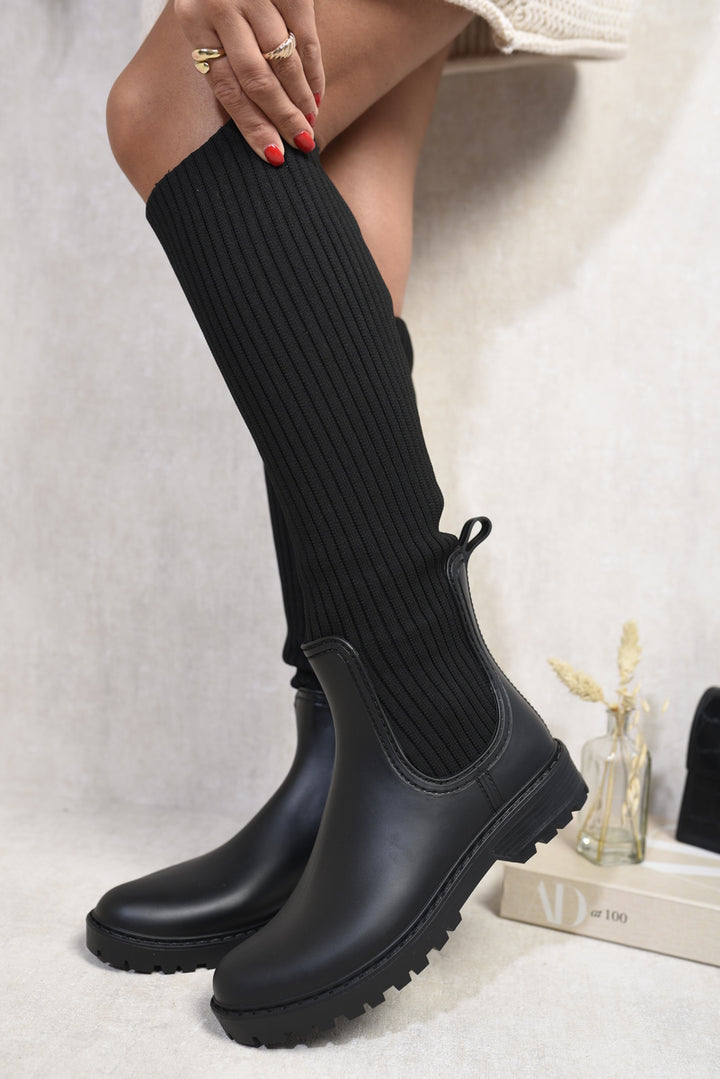 Over The Knee Sock Boots with a sleek, sock-like fit, worn by a person, showcasing modern style and sophistication. Perfect for bold fashion statements.