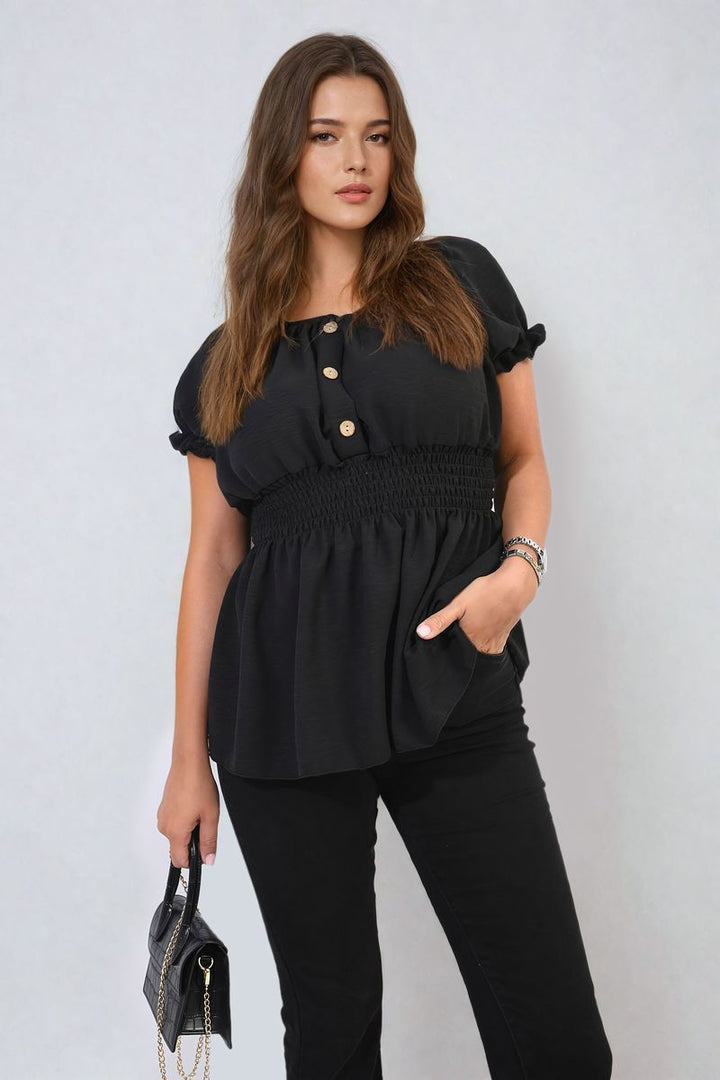 Woman in a black Button Front Cinched Waist Top, showcasing its flattering fit with a stylish button detail and adjustable waist, paired with a black purse.