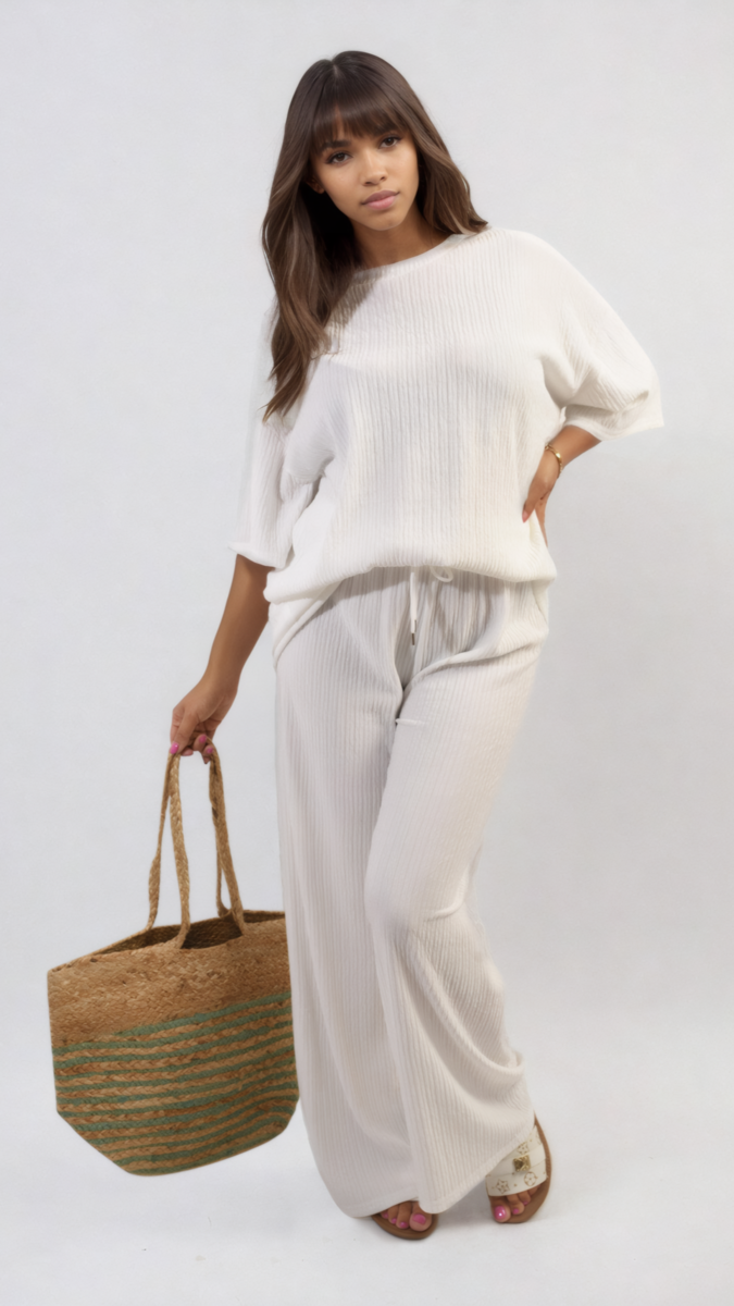 Woman in white ribbed oversized top and drawstring wide-leg trousers holding a handbag, showcasing the cozy co-ord set from Holiday Clothes UK.