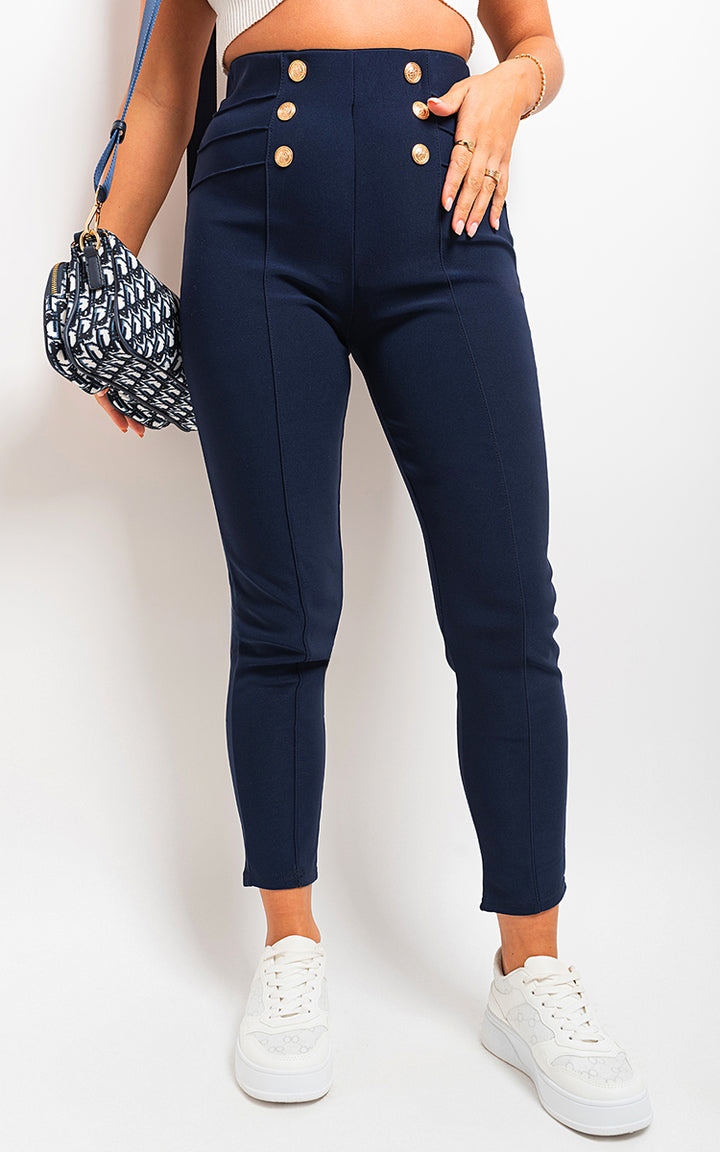 Woman in blue high-waisted button front leggings, white heels, holding a purse. This image showcases stylish leggings from Holiday Clothes UK, emphasizing comfort and sophistication.