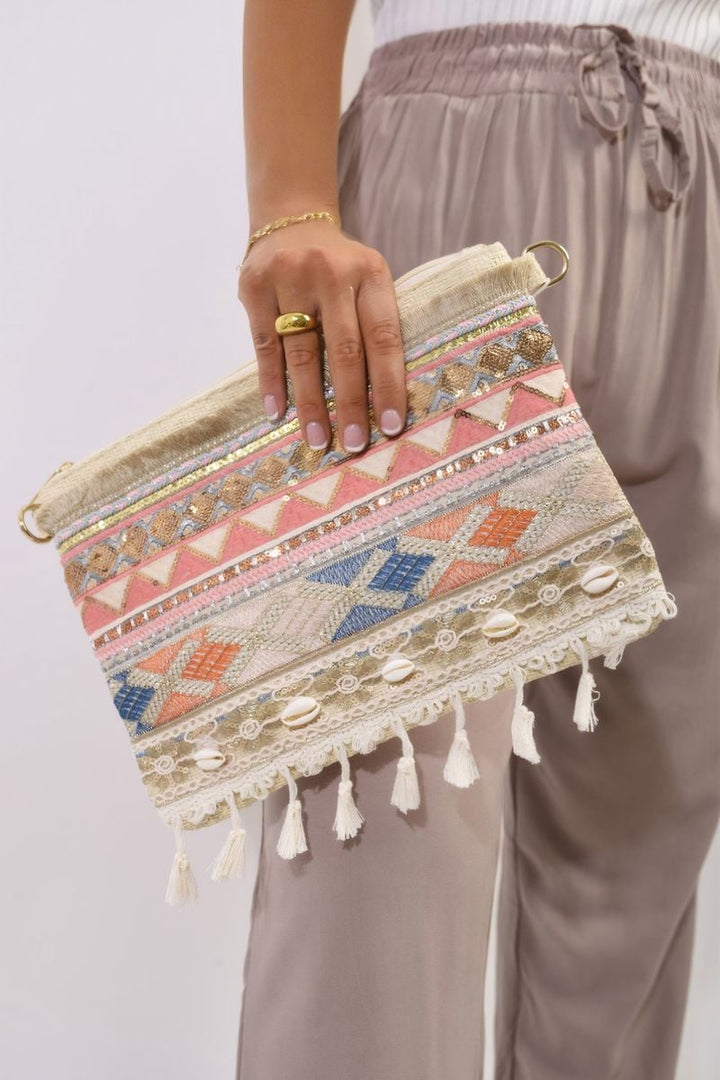 Hand holding a Deborah Pom Pom Boho Clutch Bag, featuring playful pom pom accents and intricate detailing, perfect for adding bohemian flair to any outfit.