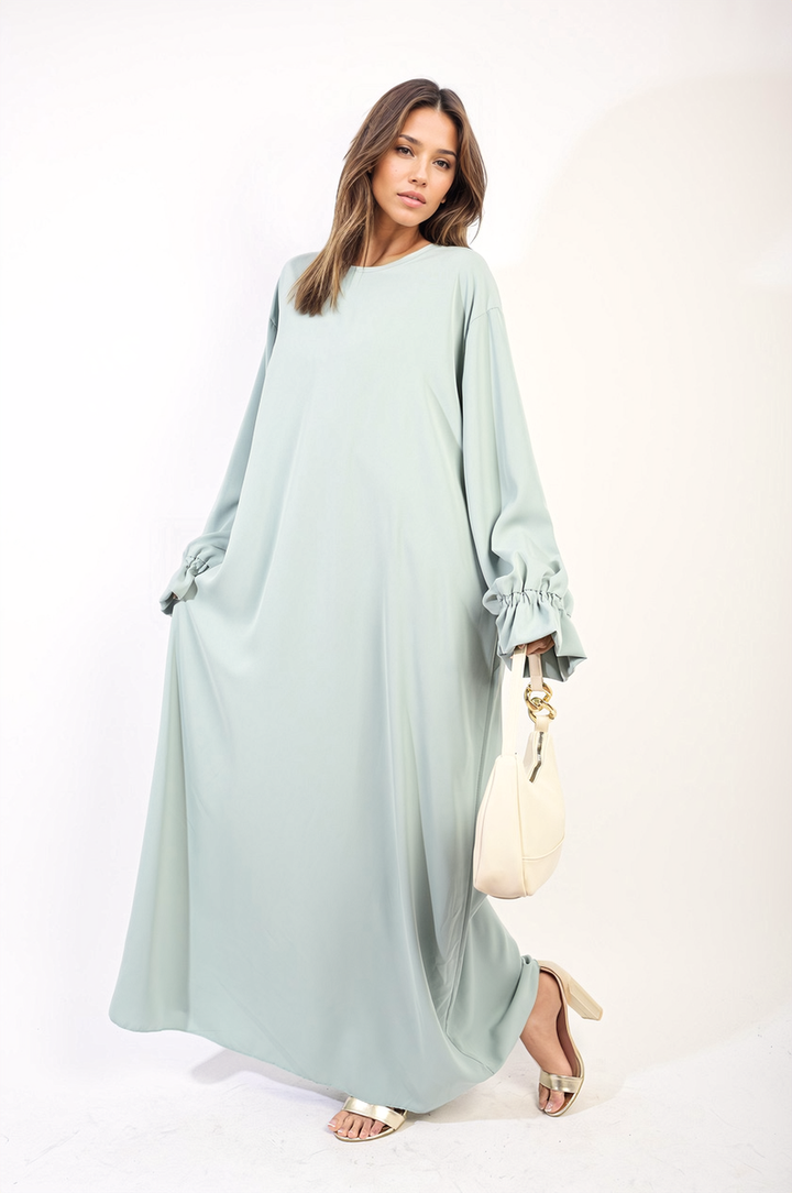 Woman in Abaya Maxi Dress with Elastic Sleeve, showcasing elegant flowing silhouette and white purse, embodying sophisticated style and comfort.