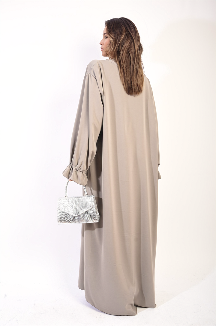 Woman in a long Abaya Maxi Dress with Elastic Sleeve, holding a silver purse, showcasing elegant and modest fashion suitable for various occasions.