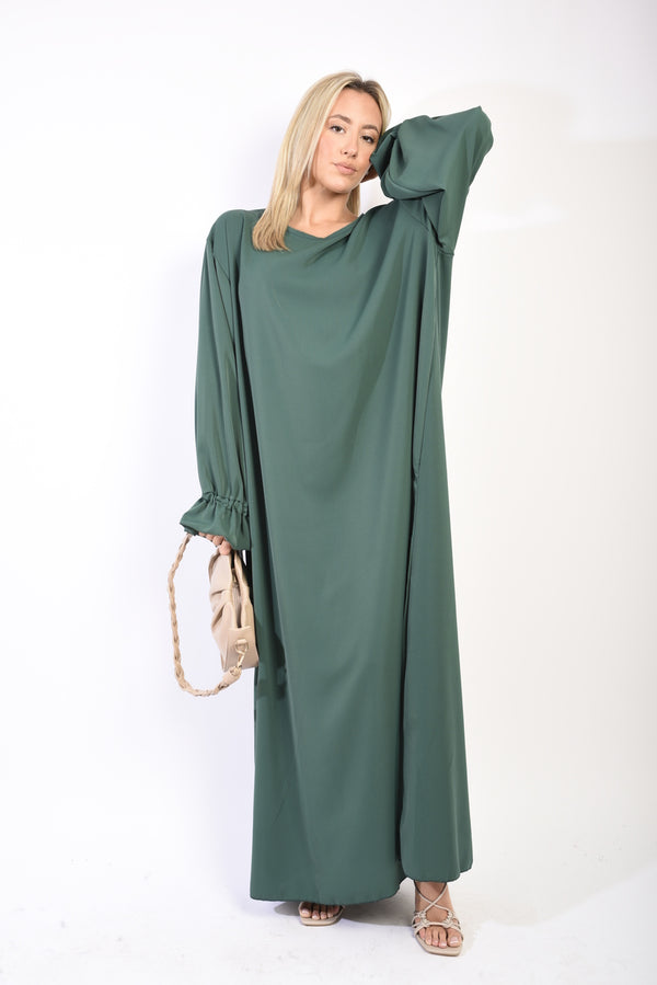 Woman in a green Abaya Maxi Dress with Elastic Sleeve, holding a purse, showcasing the dress's elegant drape and practical design.