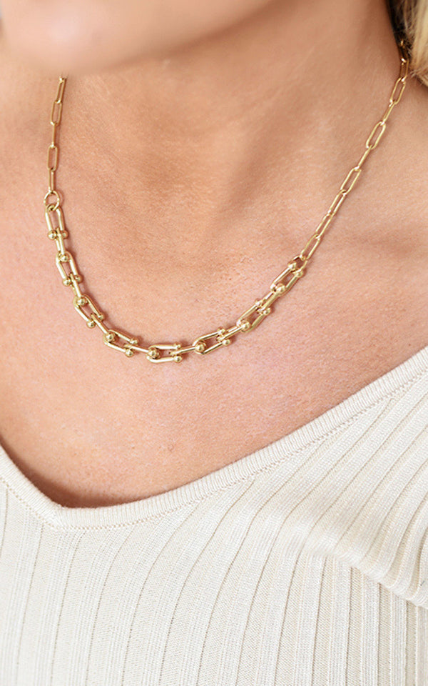 Person wearing the Paper Clip Chain Necklace, a sophisticated gold chain from ikrush, enhancing any outfit with elegance and glamour.