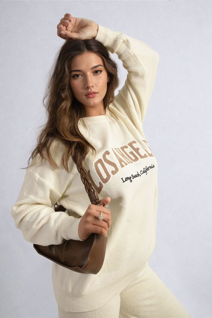 Woman wearing Los Angeles Graphic Long Sleeve Knitted Jumper, showcasing a stylish fashion accessory in a casual setting.