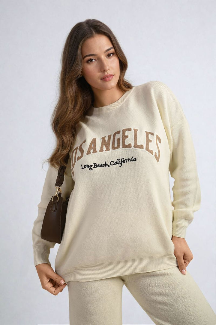 Woman modeling Los Angeles Graphic Long Sleeve Knitted Jumper, showcasing its trendy design and cozy fit, ideal for casual style from Holiday Clothes UK.