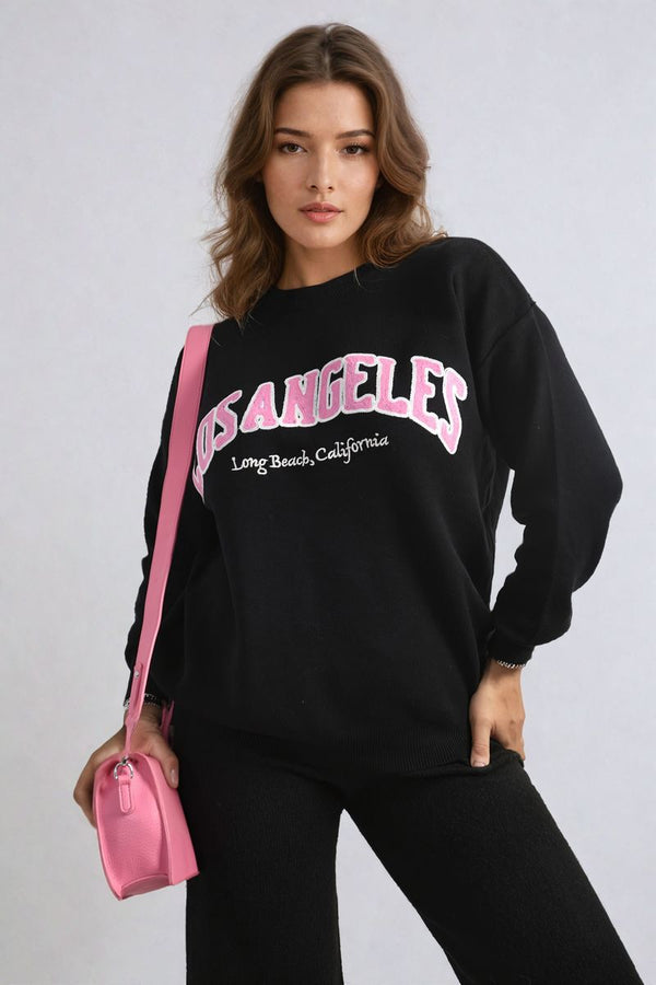 Woman wearing the Los Angeles Graphic Long Sleeve Knitted Jumper, showcasing its trendy design and cozy style, perfect for casual or holiday wear.