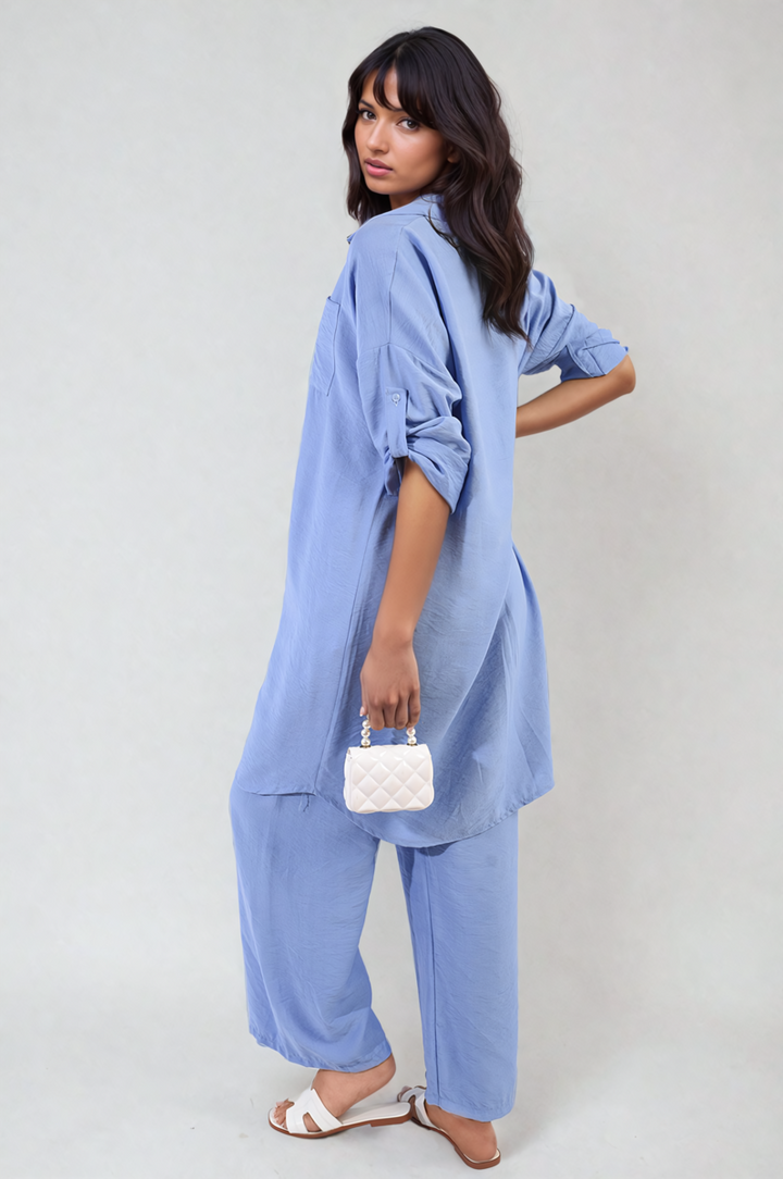 Woman wearing the Oversized Button Front Shirt & Wide Leg Pants Co-ord Set, holding a white purse, showcasing a comfortable and stylish holiday outfit.