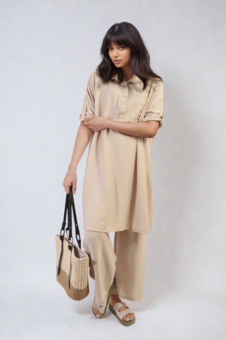 Woman in beige dress holding a bag, featuring the Dulce Oversized Button Front Shirt & Wide Leg Pants Co-ord Set, ideal for stylish, relaxed comfort.