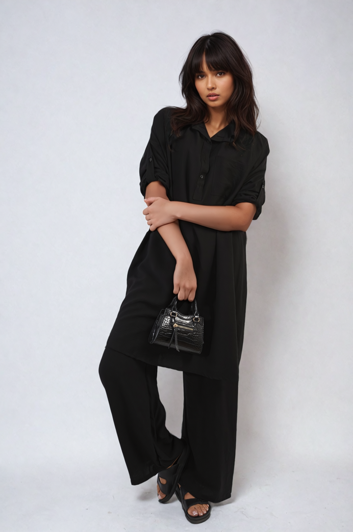 Woman wearing the Dulce Oversized Button Front Shirt & Wide Leg Pants Co-ord Set, holding a purse, showcasing a stylish and comfortable look perfect for casual outings.