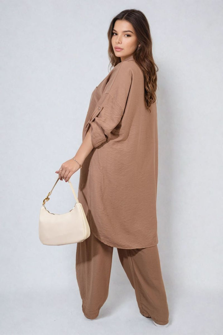 Woman wearing the Dulce Oversized Button Front Shirt & Wide Leg Pants Co-ord Set, holding a white purse, exemplifying casual yet stylish clothing from Holiday-clothes.co.uk.