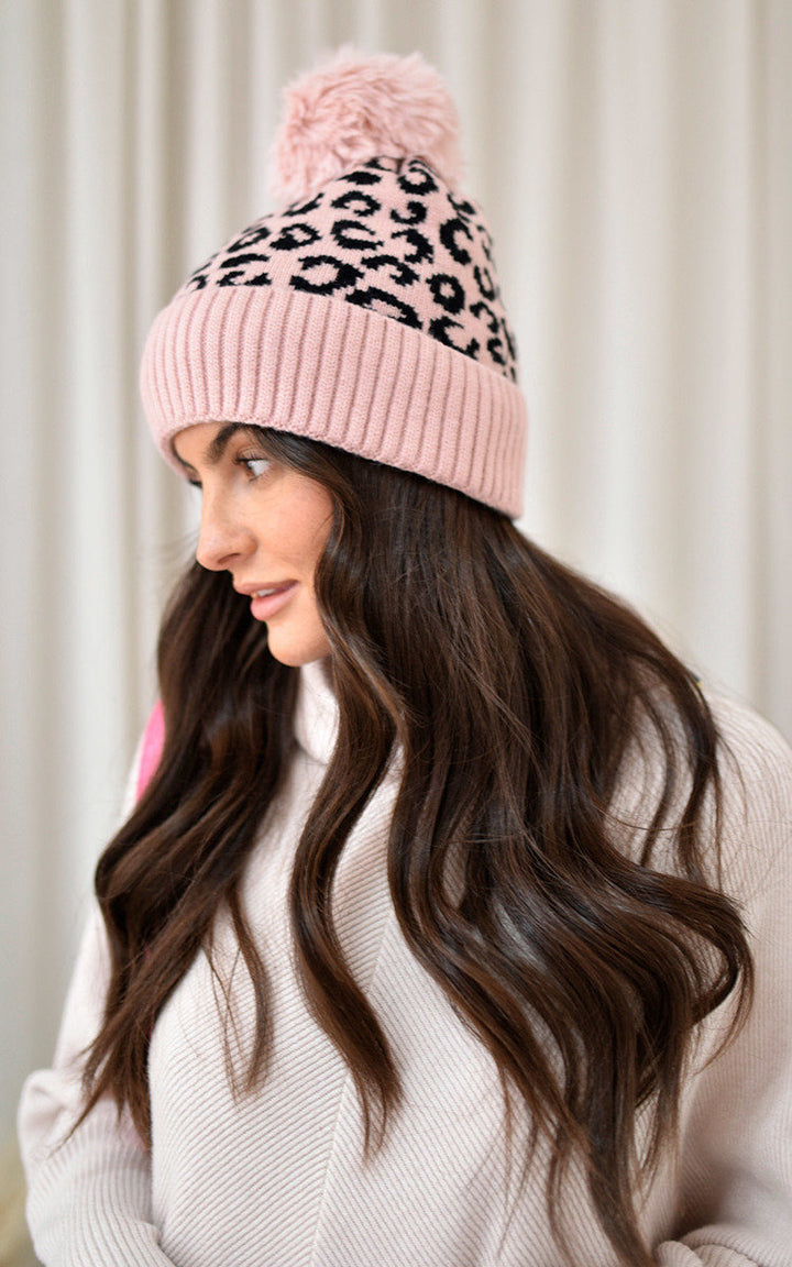 Woman wearing the Edith Faux Fur Lined Beanie Leopard Hat, featuring a cozy faux fur lining and playful pom-pom, perfect for stylish winter warmth.