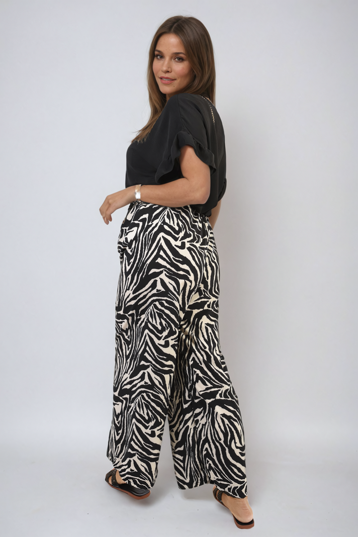 Woman modeling Zebra-Striped Print Wide Leg Trousers, featuring a stylish zebra pattern and black shirt, perfect for versatile holiday and everyday wear.