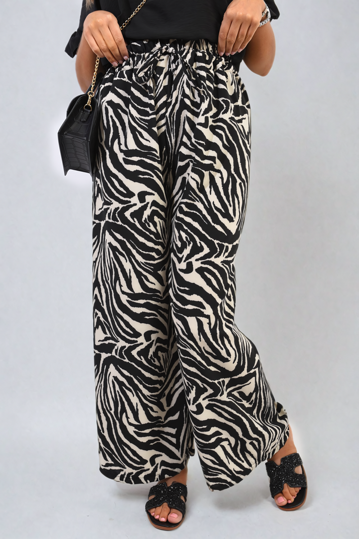 Woman wearing Zebra-Striped Print Wide Leg Trousers, holding a black purse, highlighting the trendy and versatile style of these comfortable pants.