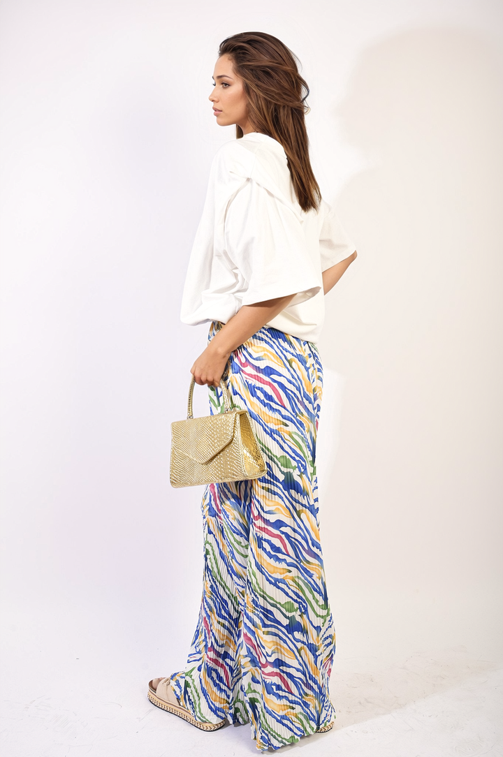 Woman in pleated wide-leg trousers with elastic waist, holding a purse, showcasing their elegant and versatile design.