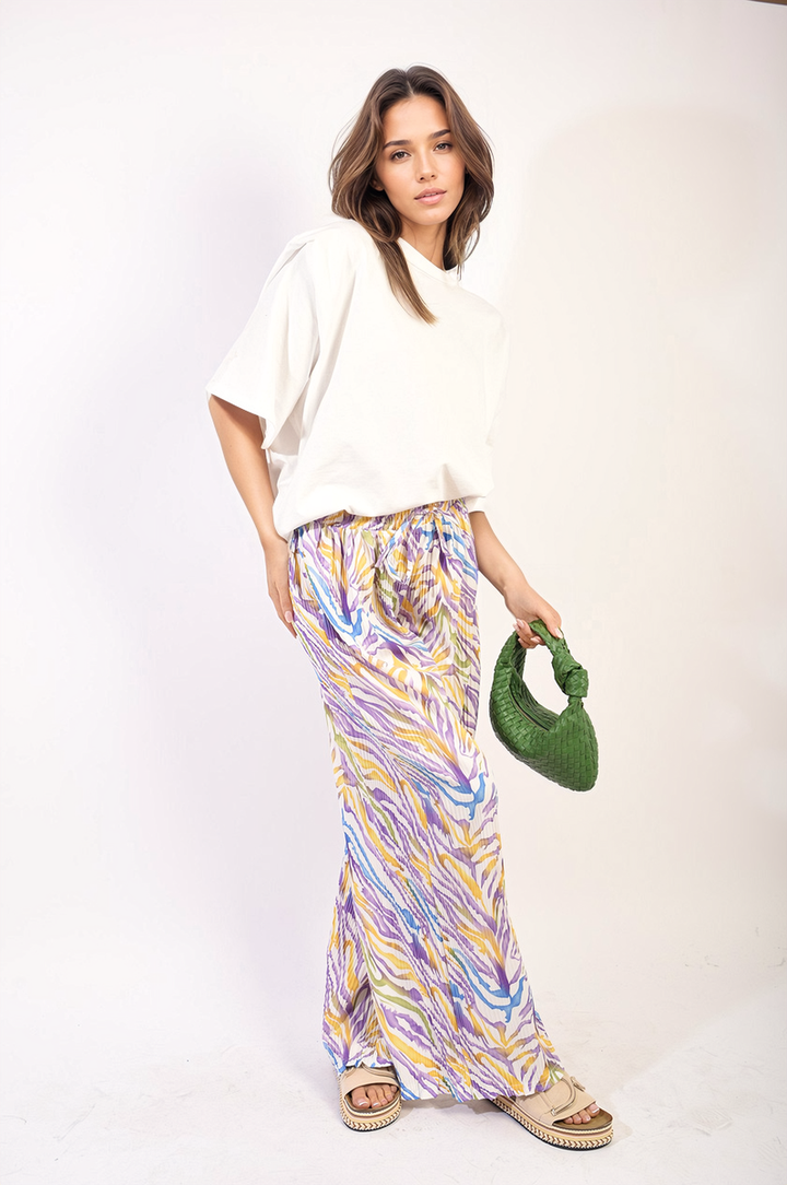 Woman in a long skirt holding a green purse, highlighting the Pleated Wide Leg and Elastic Waist Trousers, perfect for stylish holiday and everyday wear.