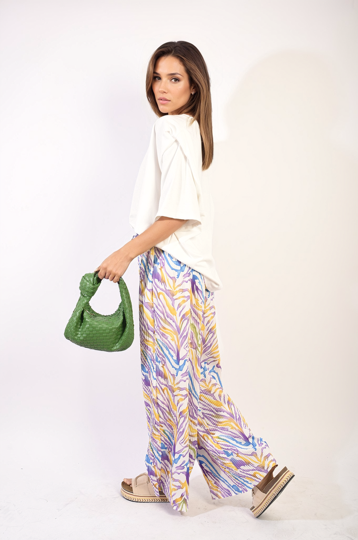 Woman holding a green purse, showcasing Pleated Wide Leg and Elastic Waist Trousers, emphasizing stylish comfort and sophistication for versatile occasions.