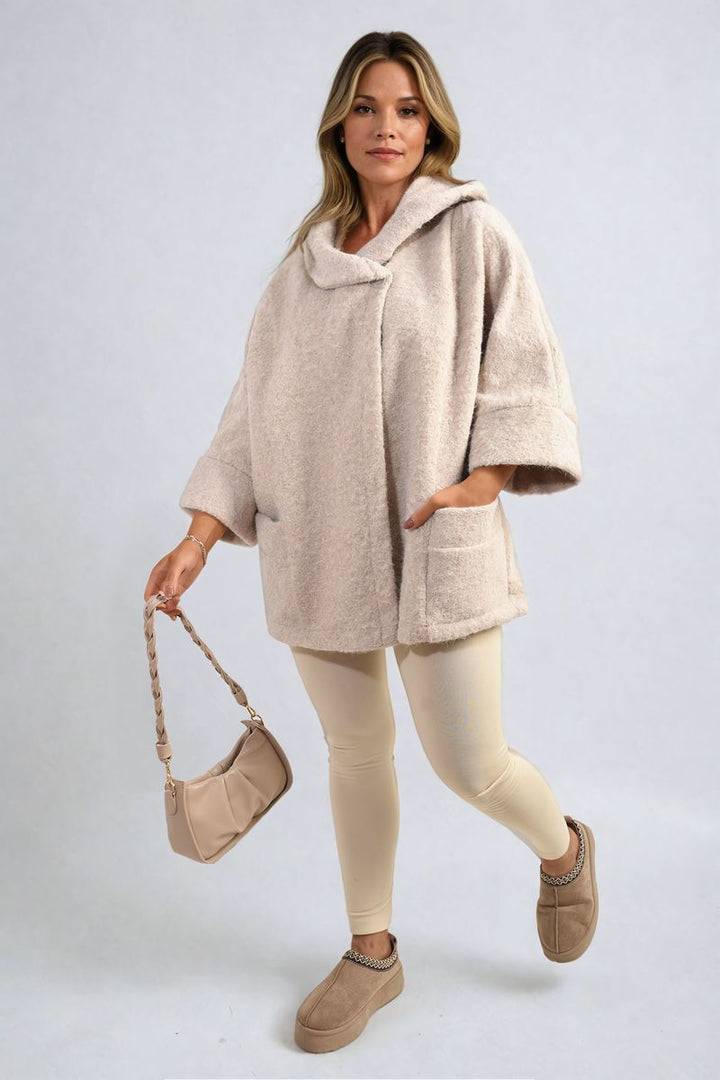 Woman in a Cowl Neck Oversized Cape Jacket holding a purse, showcasing the jacket's cozy cowl neck and trendy oversized fit.