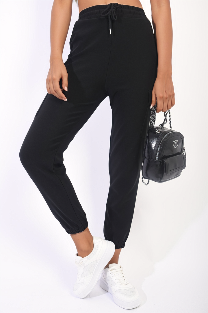 Person wearing Eloisa Cargo Pocket Trouser with Drawstring, showcasing multiple cargo pockets and a comfortable fit, paired with white sneakers and a black bag.