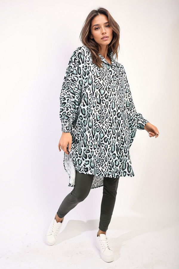 Woman in an oversized long sleeve leopard print shirt dress, styled with white sneakers, showcasing a bold and versatile fashion statement.