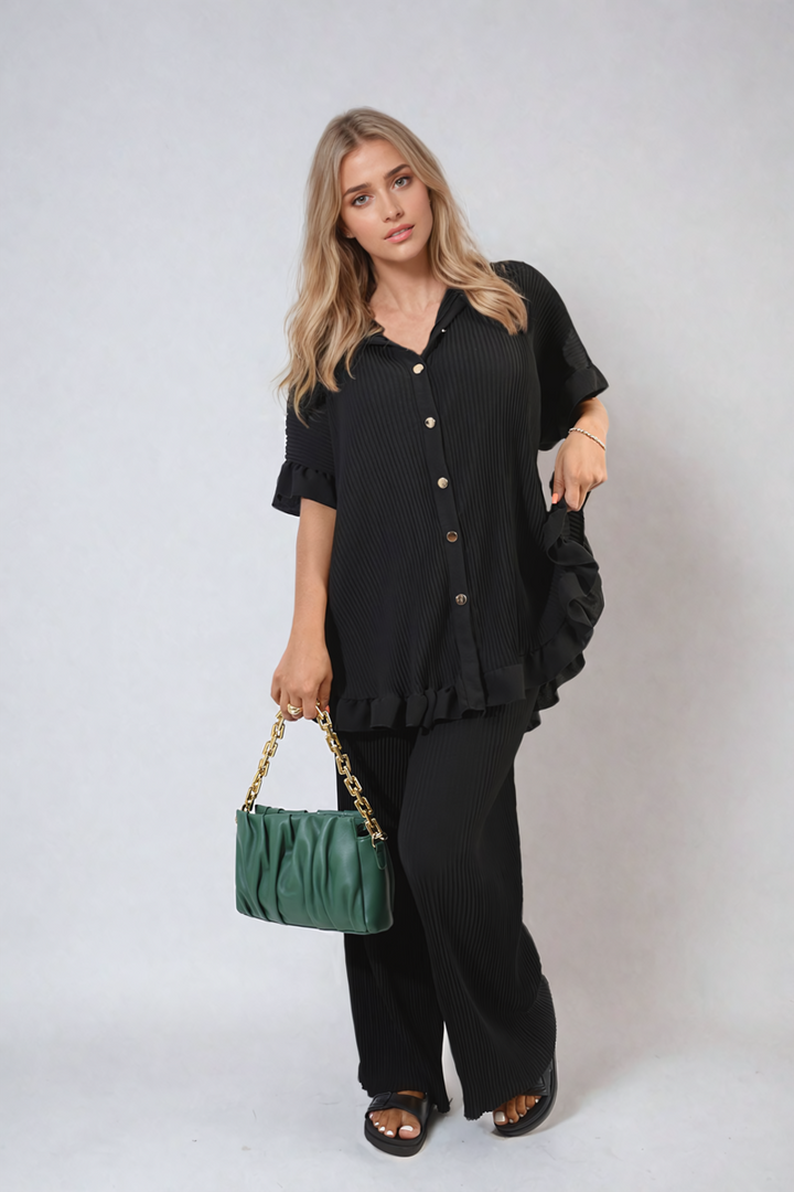 Woman in a black outfit showcasing the Emily Button Pleated Frill Ruffle Top and Wide Leg Trouser Co-ord Set, holding a green purse.