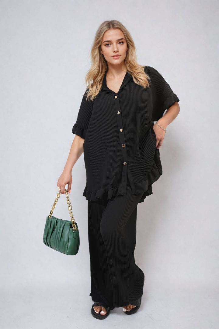 Woman wearing Button Pleated Frill Ruffle Top and Wide Leg Trouser Co-ord Set, holding a green purse, showcasing fashionable elegance and versatility.