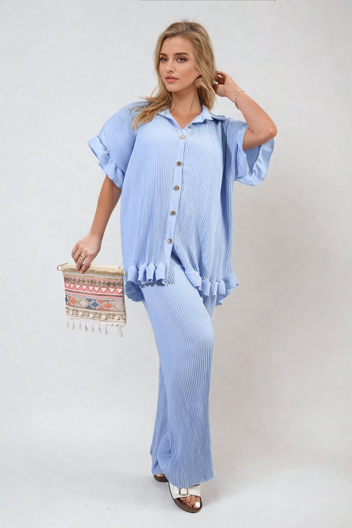 Woman in a blue Button Pleated Frill Ruffle Top and Wide Leg Trouser Co-ord Set, holding a colorful bag, showcasing holiday-ready elegance from Holiday-clothes.co.uk.