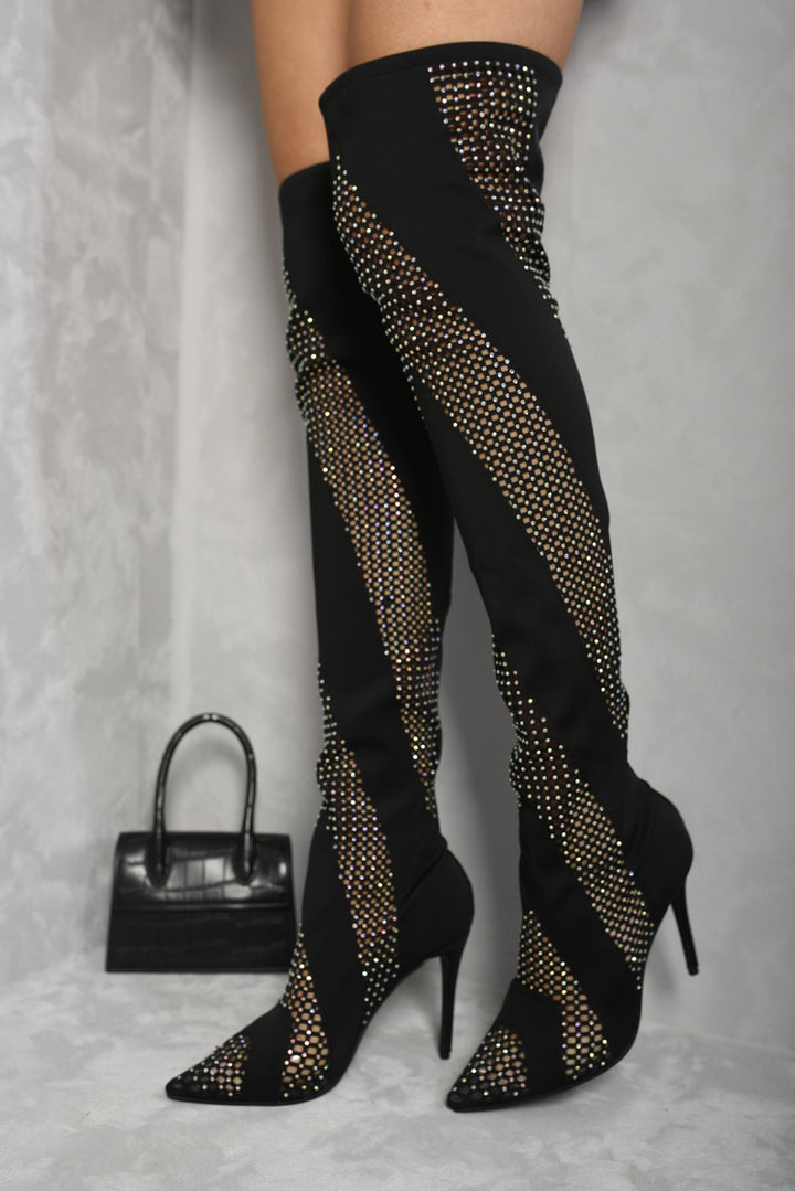 Person wearing Rhinestone Mesh Knee High Boots sparkling with rhinestones, paired with black pants and holding a black purse, showcasing stylish footwear.