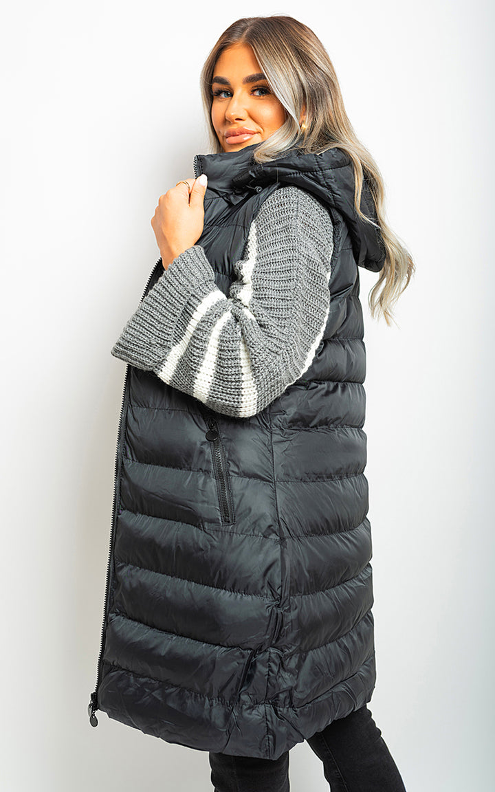 Woman wearing a Hooded Longline Quilted Gilet, showcasing its quilted warmth and hooded design, perfect for stylish layering and outdoor adventures.