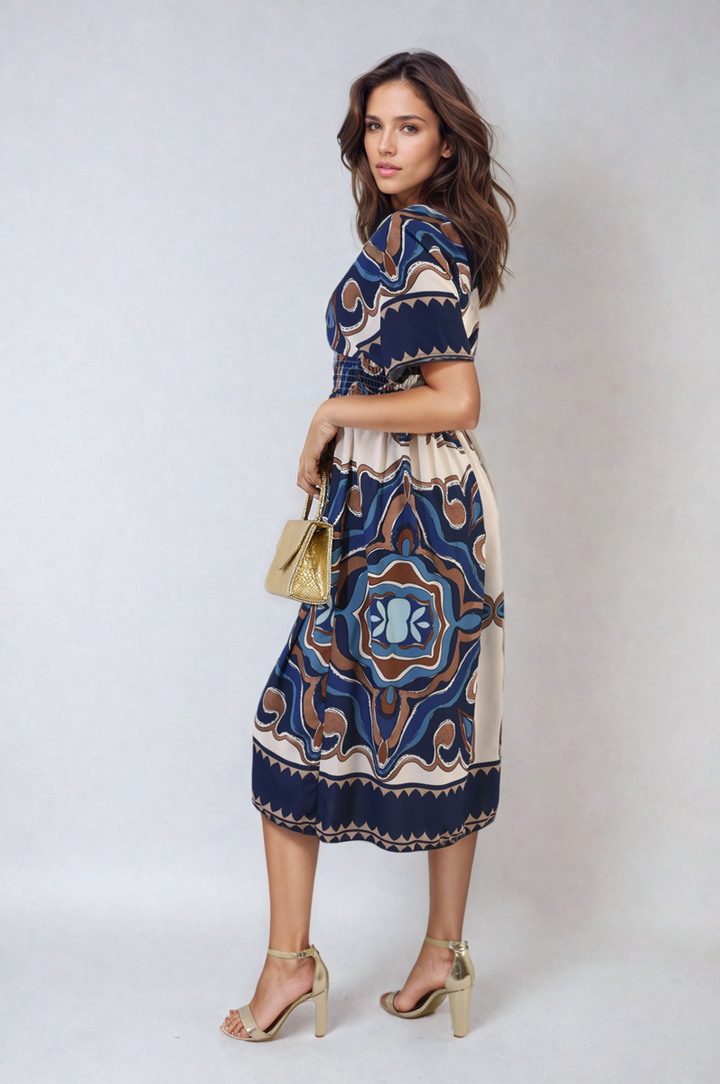 Woman modeling the Ruched Printed V-Neck Short Sleeve Midi Dress, paired with gold high-heeled shoes and a gold purse, showcasing a chic casual outfit.