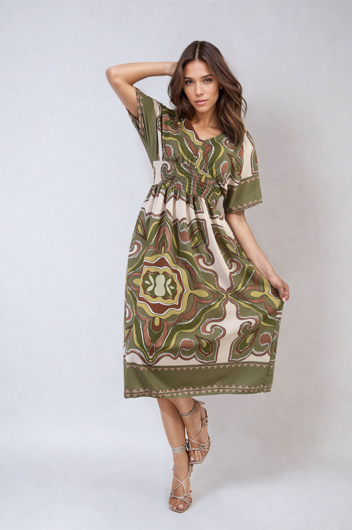 Woman wearing an Estella Ruched Printed V-Neck Short Sleeve Midi Dress, showcasing its chic ruched design and pattern, perfect for casual occasions.