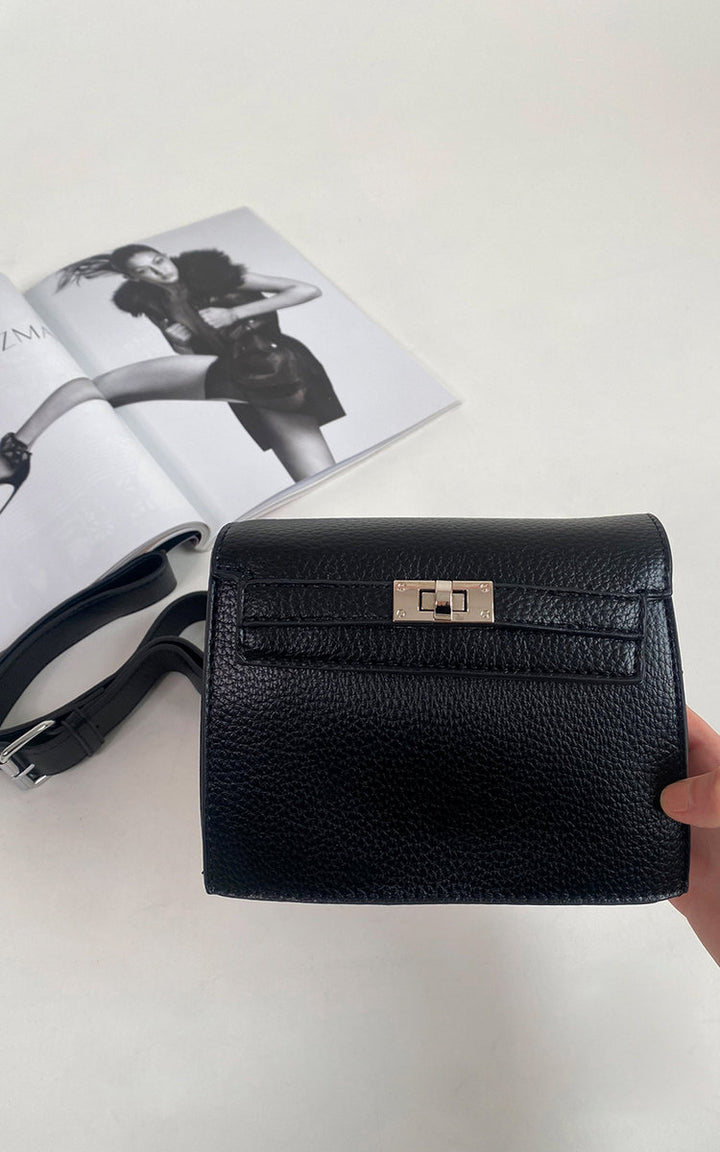 Hand holding a black leather purse with a silver clasp, showcasing the Faux Leather Crossbody Bag with Adjustable Strap, ideal for everyday use.