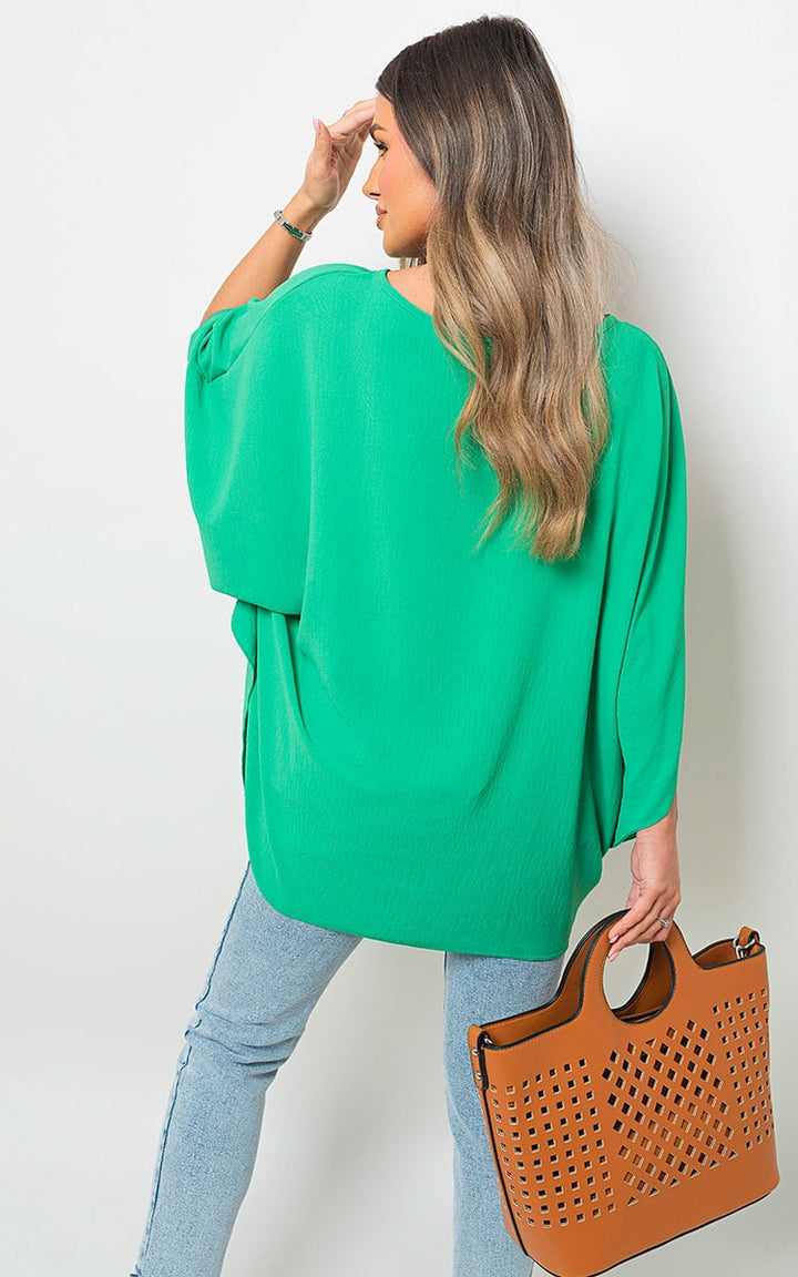 Woman wearing an Oversized Batwing Sleeve Casual Top, holding a brown handbag, showcasing the top's relaxed fit and stylish batwing sleeves.