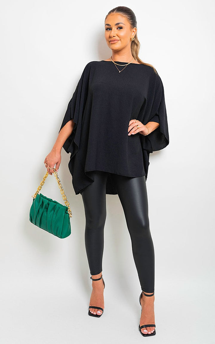 Woman in black outfit holding a green purse, showcasing the Fatima Oversized Batwing Sleeve Casual Tops with stylish, flowy batwing sleeves for a chic, relaxed look.