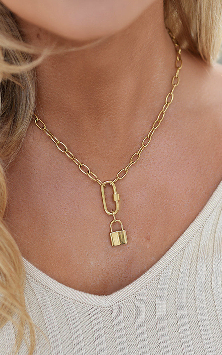 Woman wearing the Faye Lock Pendant Necklace, a stylish gold chain with adjustable locking mechanism, perfect for adding personality to any outfit.