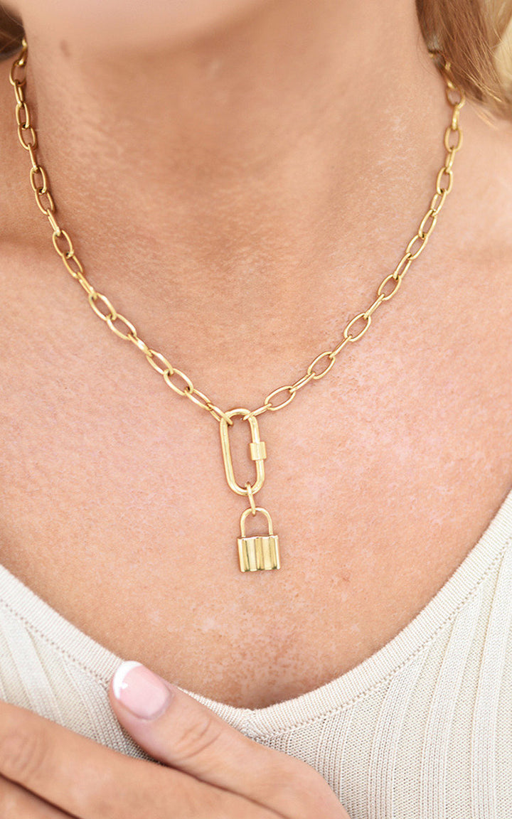 Person wearing the ikrush/Faye Lock Pendant Necklace, a stylish gold chain with a unique adjustable lock pendant, perfect for enhancing any outfit.