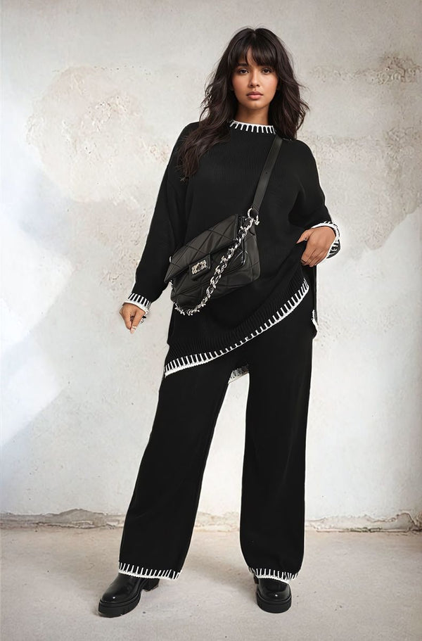 Woman in a black knitted co-ord set with blanket stitch detail, holding a black bag. The set features a cozy knit design, ideal for stylish comfort.