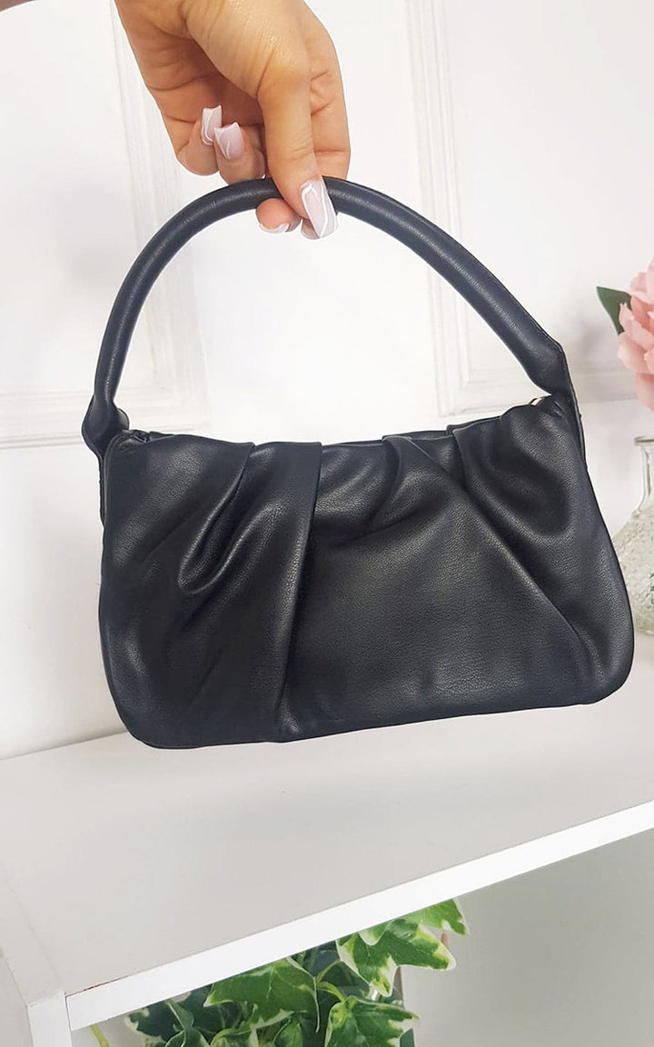 Hand holding the Pouch Shoulder Handbag in black, showcasing its faux leather and stylish pouch detail, ideal for versatile daily use.