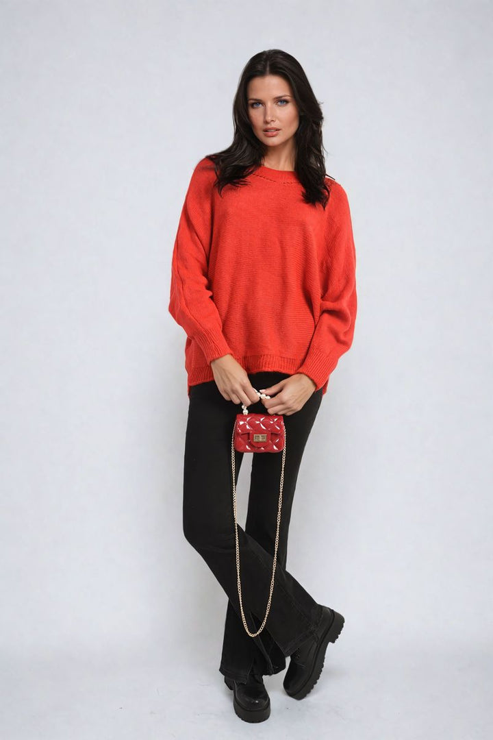 Woman wearing the Florencia Crew Neck Back Patterned Knitted Jumper, showcasing its cozy, chic design. She holds a red purse, highlighting casual style.