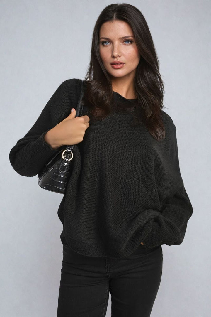 Woman in black sweater holding a Crew Neck Back Patterned Knitted Jumper, showcasing its cozy and chic design, ideal for casual outings.