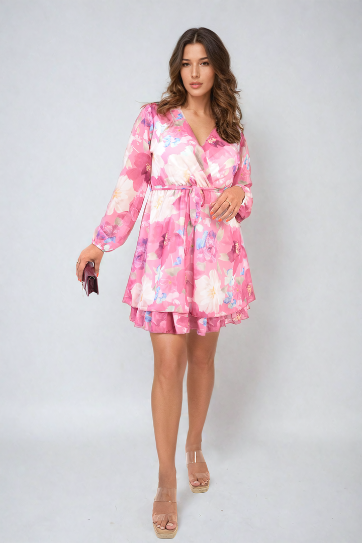 Woman wearing Francesca Floral Tie Front Tiered Mini Dress, featuring tiered skirt and front tie detail, styled with clear strap sandals.