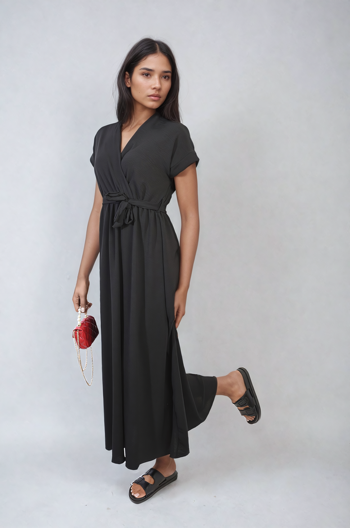 Woman in a black Wrap Tie Waist Short Sleeve Midi Dress, accessorized with a red purse. The dress features a wrap design and adjustable tie waist.