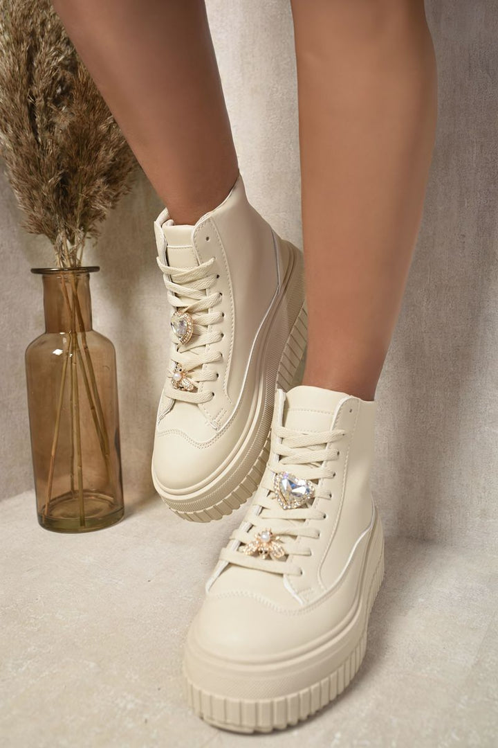 White high-top platform trainers with decorative jewel details, showcasing stylish footwear ideal for casual outings or parties.